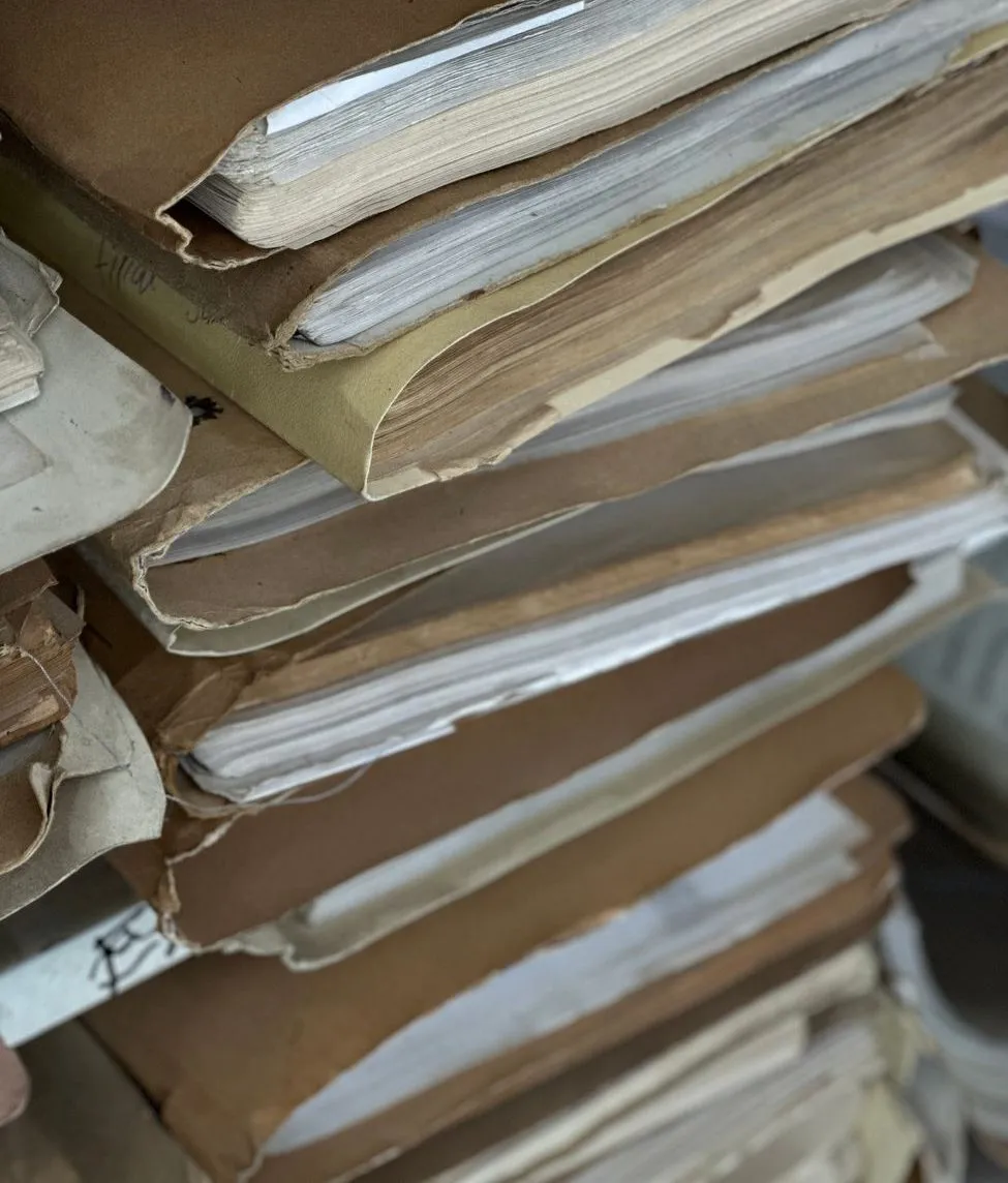 Stacks of worn brown company files, thick with papers