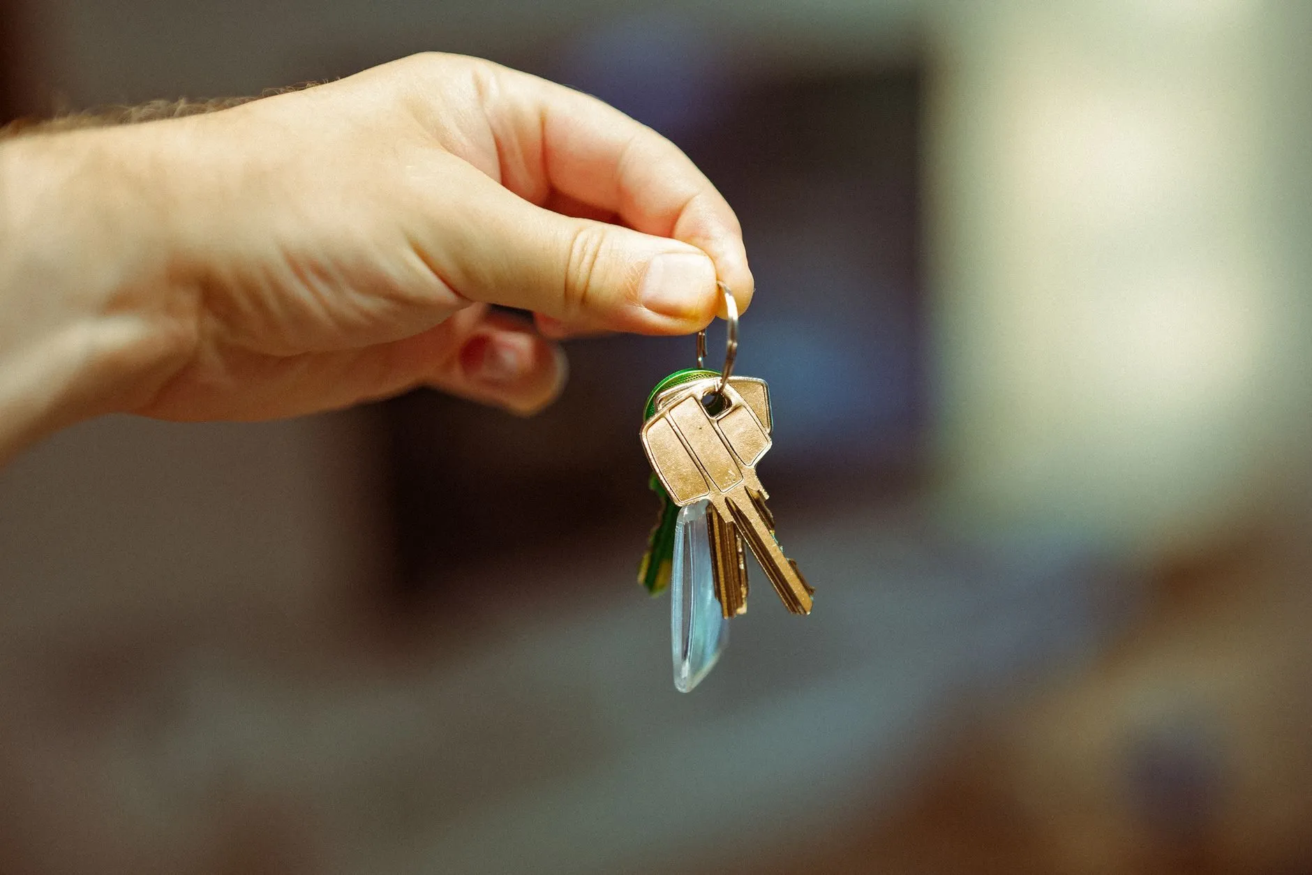 A hand holding up a bunch of house keys inside a flat