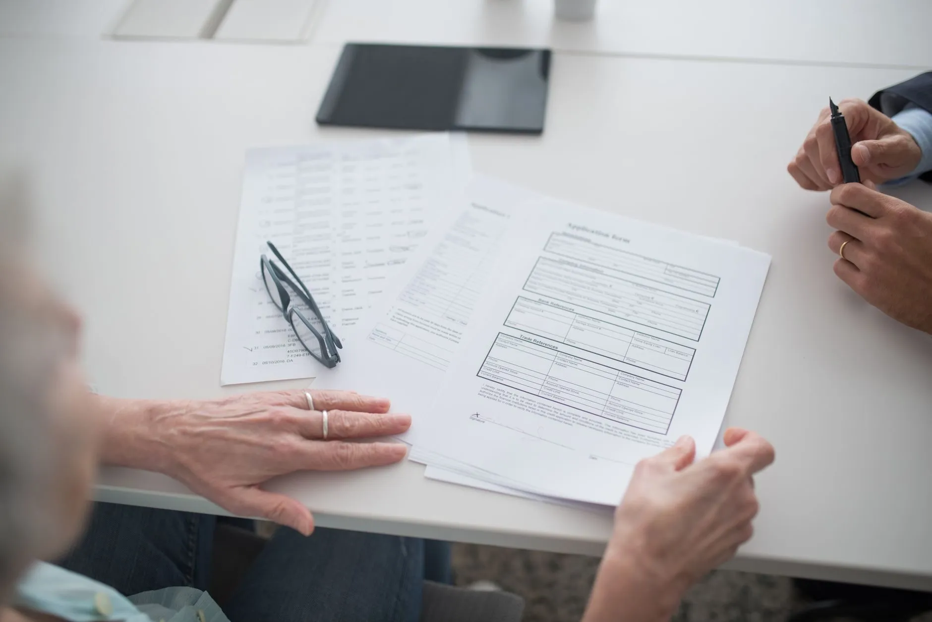 Two people going through printed forms across a white table