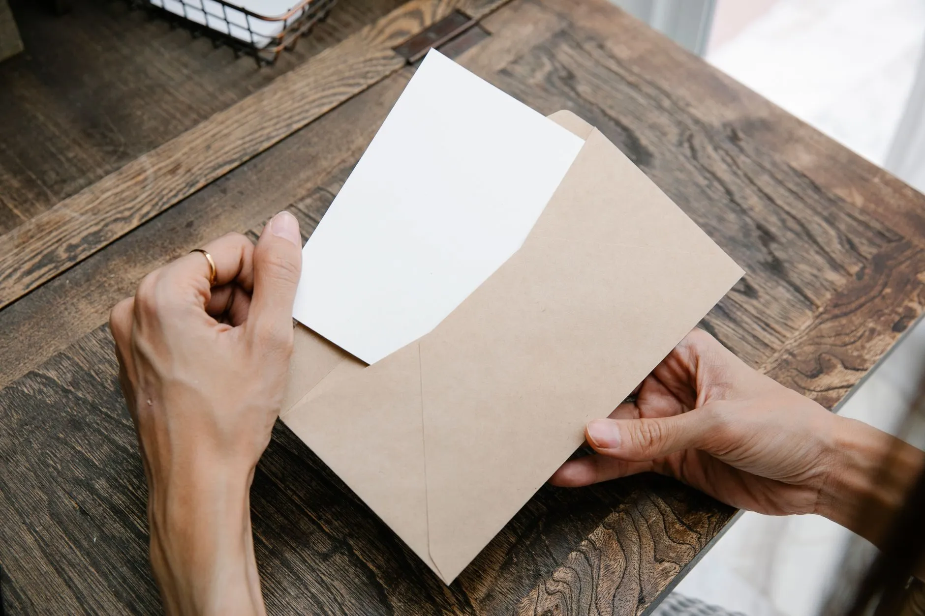 A payslip being slipped into a brown envelope on a wooden table